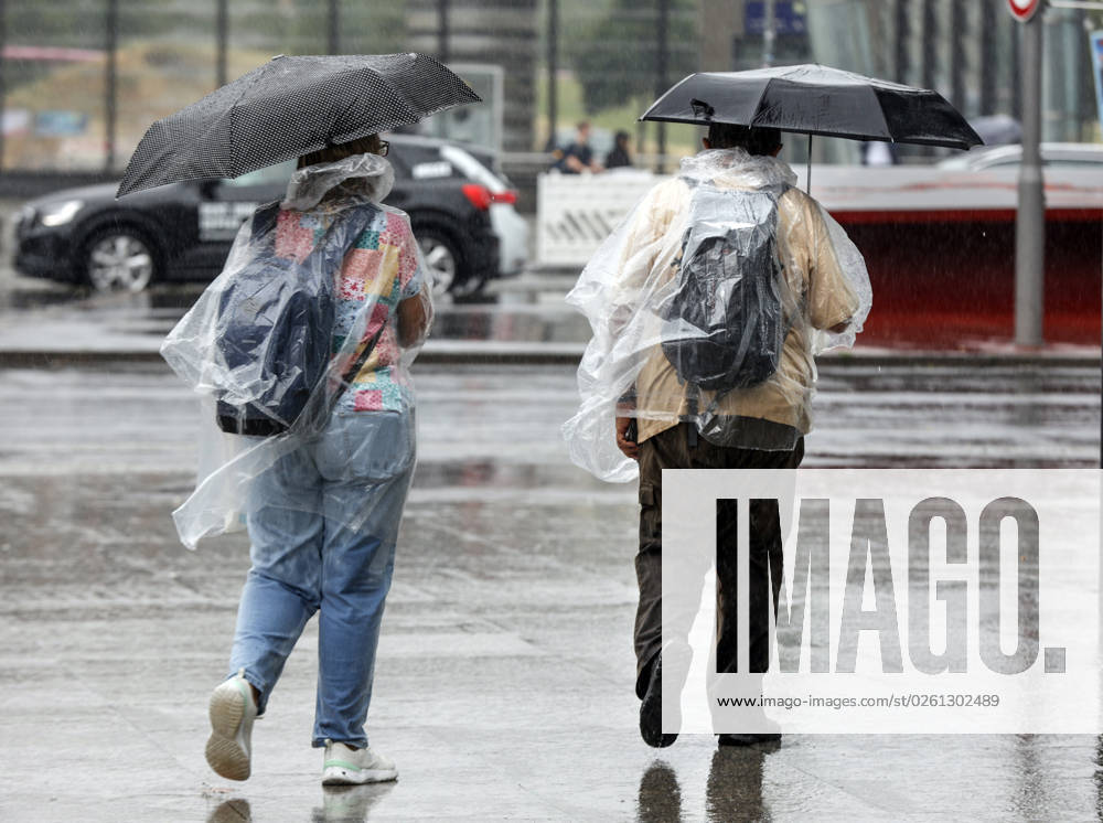 -Touristen schuetzen sich mit Regencapes und Regenschirmen vor starkem Regenfall. Starke Unwetter sind ueber Teile Deutschlands gezogen. Berlin Berlin Deutschland