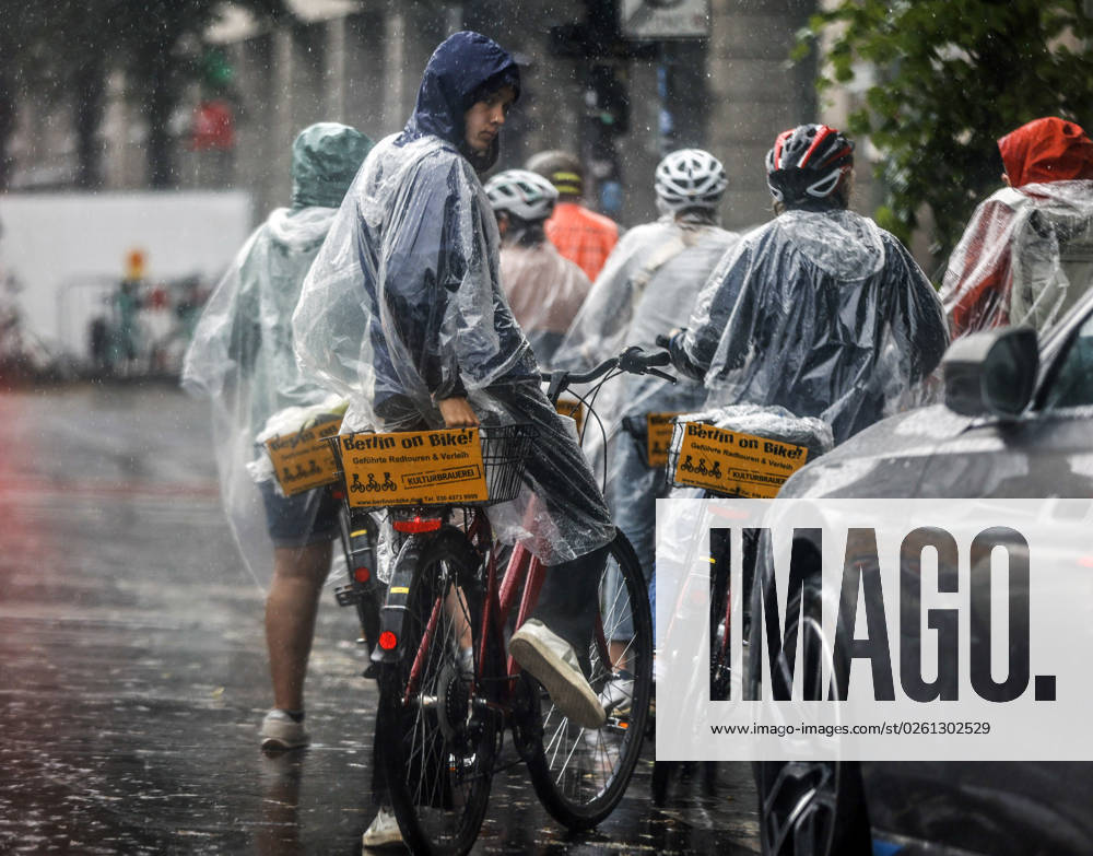 -Touristen einer Berlin On Bike Fahrradtour schuetzen sich mit Regencapes vor starkem Regenfall. Starke Unwetter sind ueber Teile Deutschlands gezogen. Berlin Berlin Deutschland