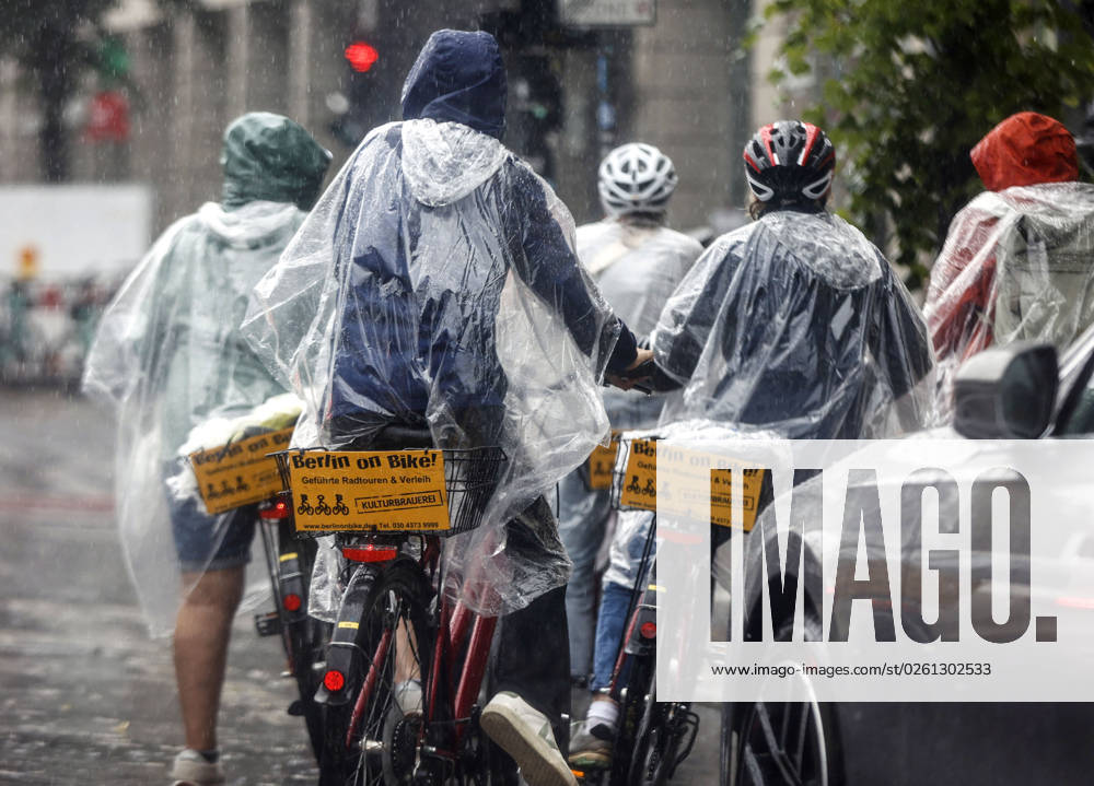 -Touristen einer Berlin On Bike Fahrradtour schuetzen sich mit Regencapes vor starkem Regenfall. Starke Unwetter sind ueber Teile Deutschlands gezogen. Berlin Berlin Deutschland