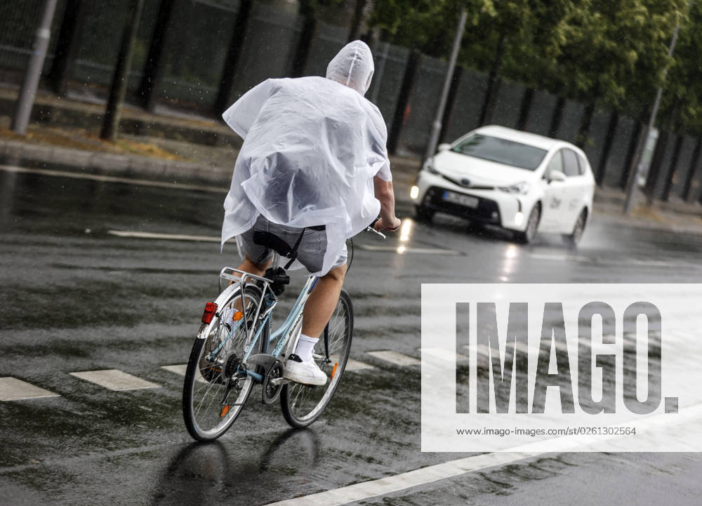 - Ein Fahrradfharer schuetzt sich mit einem Regencape vor starkem Regenfall. Starke Unwetter sind ueber Teile Deutschlands gezogen. Berlin Berlin Deutschland