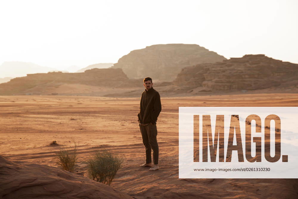 Young man with hands in pockets standing in desert at sunset model released, Symbolfoto, PCLF00562