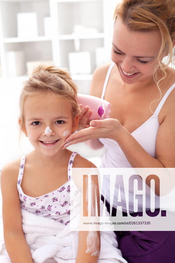 Beauty ritual - little girl and mother applying body lotion after bath