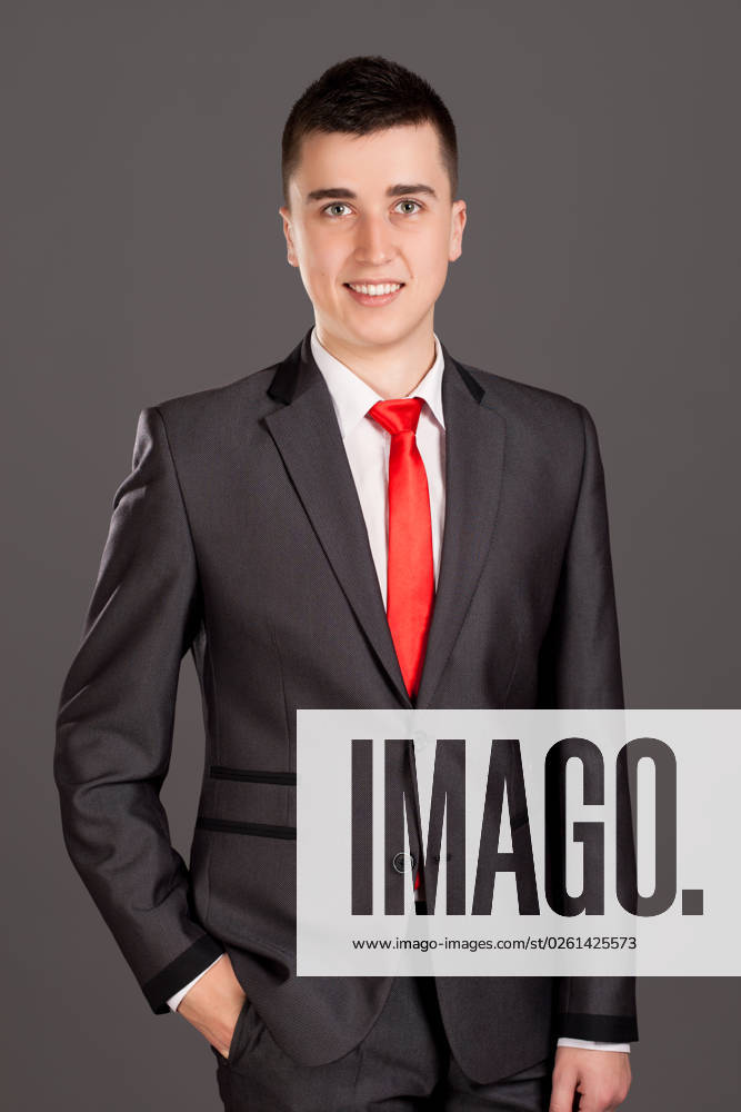 Portrait of young businessman standing on grey background