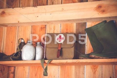 Retro medic equipment on an old wooden shelfe with boots and water bottles accident, aid, ambulance, army, background, bag, boots, care, combat, cross, detail, doctor, emergency, equipment, fabric, first, grunge, health, healthcare, help, hospital, hurt, injury, insurance, jute, kit, medic, medical, medicine, military, object, old, pharmacy, red, rescue, retro, rustic, safety, shelfe, supplies, symbol, texture, travel, treatment, vintage, war, water, weathered, white, wood