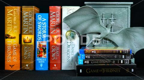 ADELAIDE, SOUTH AUSTRALIA - JULY 12, 2017: Popular fantasy hardcover books, A Song of Ice and Fire, by George R R Martin, with Game of Thrones dragon cover DVD collection, front focus. a, song, of, fire, and, ice, author, authorised, authorized, background, bestseller, black, book, series, bookends, books, closeup, collection, collectors edition, cover, creator, dragon, dvd, fantasy, game of thrones, george r r martin, hardcover, hbo, house stark, illustrative editorial, pop culture, pop up, popular, program, reveal, saga, science fantasy, science fiction, show, slider, slow, television, title, tv, video, westeros