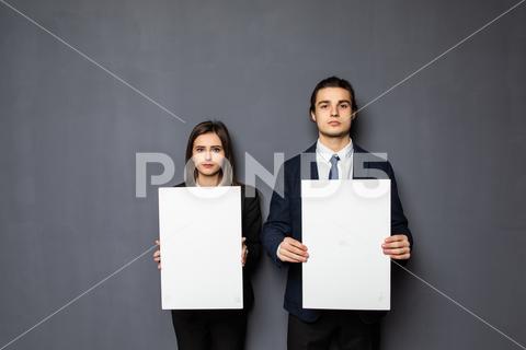 Confident business couple standing with blank board to advertise or invite on gray background background, woman, business, hand, love, person, girl, couple, man, school, banner, paper, young, isolated, space, happy, blank, showing, board, female, male, casual, studio, smile, presentation, white, billboard, guy, job, feeling, portrait, work, copy, together, posing, surprised, product, caucasian, camera, boyfriend, relationship, romantic, expression, presenting, adult, gesture, two, people, message, invitation