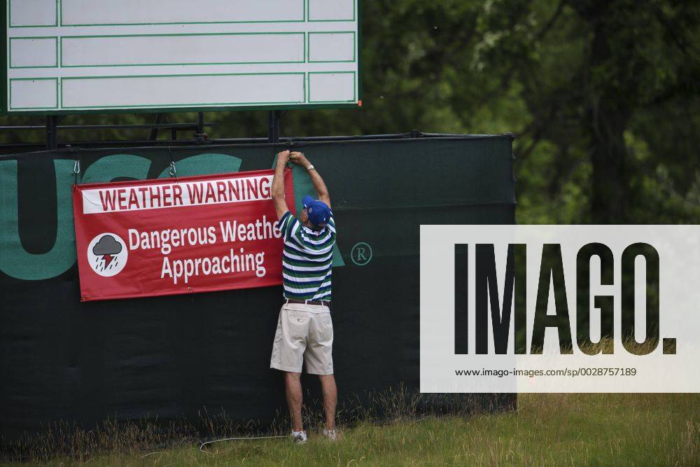 En funktionär sätter upp en skylt som varnar för ett oväder som drar in över golfbanan Erin Hills inför golfturneringen US Open den 14 juni 2017 i Hartford.