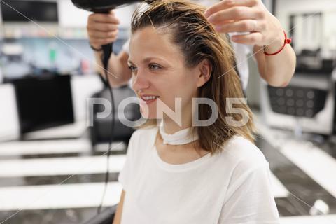 Woman in a beauty salon dry her head with hairdryer. Hair styling training concept woman, portrait, hairdryer, master, wet, hair, hairdresser, beauty, salon, training, hairstyles, styling, workplace, hairstylist, professional, style, fashion, stylist, studio, grooming, concept, closeup, haircut, comb, wig, bob, bangs, curls, strands, hairbrush, drying, hairstyle, curling, air, shampooing, shampoo, client, visitor, service, hold, people, customer, work, equipment, straight, glamour, barber, beautiful, services