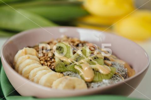 A shot of chia pudding breakfast dish with fresh kiwi and banana with a yellow tulip in background. abstract, aesthetic, art, background, banana, bowl, breakfast, chia, colorful, concept, contemporary, creative, delicious, design, dessert, detox, diet, fashion, food, fresh, fruit, granola, green, healthy, hipster, idea, kiwi, lifestyle, lunch, minimal, modern, oatmeal, organic, pastel, pattern, pudding, raw, seed, spoon, still, tasty, trend, vegan, vegetarian, visual, yellow, yogurt