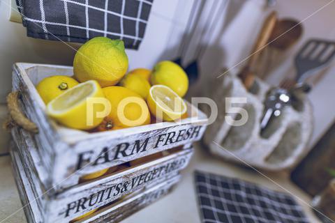 Kitchen Interior. Selective Focus on a Box with Fresh Ripe Lemons. Tasty Citrus Fruits for Lemonade. Home Life. Healthy Organic Nutrition. background, citrus, clean, cooking, cozy, decor, detail, diet, eat, eating, farm fresh, food, fresh, freshness, fruit, fruits, furnishing, furniture home, healthy, household, indoor, ingredient, interior decoration, interior design, interior home, items, juicy, kitchen, kitchen tools, lemon, lemonade, lemons, luxury interior, modern, new, nobody, nutrition, objects, plant, preparation, ripe, rustic, selective focus, stylish, table, table top, vegetables, vitamin, vitamins, yellow