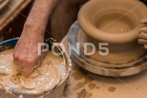 Crop unrecognizable sculptor with equipment giving shape while sculpting with brown clay on throwing wheel man, shape, clay, sculpt, equipment, process, motion, jug, ceramic, skill, male, sculptor, workshop, art, artist, handicraft, earthenware, ceramist, craft, create, dirty, form, hobby, handmade, maker, master, molding, occupation, pottery, utensil, wet, wheel, professional, work, artisan, throw, small business, talent, workplace, crop, unrecognizable, faceless, anonymous, horizontal, body part, blur, indoors, top view, from above