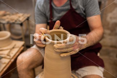 Crop unrecognizable sculptor with equipment giving shape while sculpting with brown clay on throwing wheel man, shape, clay, sculpt, equipment, process, motion, jug, ceramic, skill, male, sculptor, workshop, art, artist, handicraft, earthenware, ceramist, craft, create, dirty, form, hobby, handmade, maker, master, molding, occupation, pottery, utensil, wet, wheel, professional, work, artisan, throw, small business, talent, workplace, crop, unrecognizable, faceless, anonymous, horizontal, body part, blur, indoors