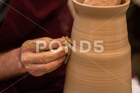 Crop unrecognizable sculptor with equipment giving shape while sculpting with brown clay on throwing wheel man, shape, clay, sculpt, equipment, process, motion, jug, ceramic, skill, male, sculptor, workshop, art, artist, handicraft, earthenware, ceramist, craft, create, dirty, form, hobby, handmade, maker, master, molding, occupation, pottery, utensil, wet, wheel, professional, work, artisan, throw, small business, talent, workplace, crop, unrecognizable, faceless, anonymous, horizontal, body part, blur, indoors