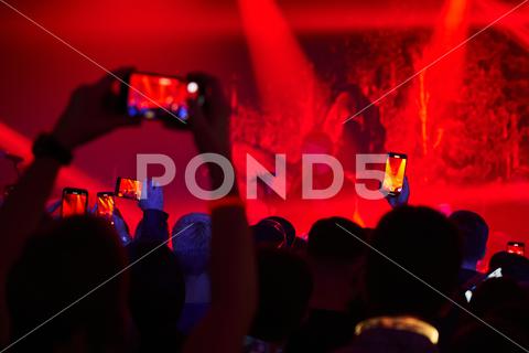 Crowd hands at a concert in red light with phones that are videotaping. High quality photo concert, crowd, entertainment, event, music, people, popular, silhouette, young, audience, background, cheerful, festival, group, happy, live, rock, youth, musical, musician, blue, excitement, singer, song, star, many, cheer, excited, fans, full, grand, great, heads, lots, multitude, packed, youthful, band, dance, fun, nightlife, party, performance, pop, stage, celebration, club, disco, fan