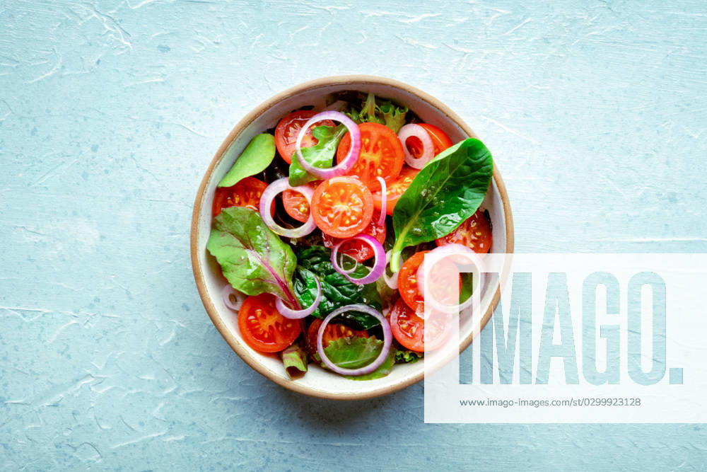 Salad with tomato, fresh leaves, and onions, overhead flat lay shot Salad with tomato, fresh leaves, and onions, overhead flat lay shot. Healthy diet, simple vegan recipe