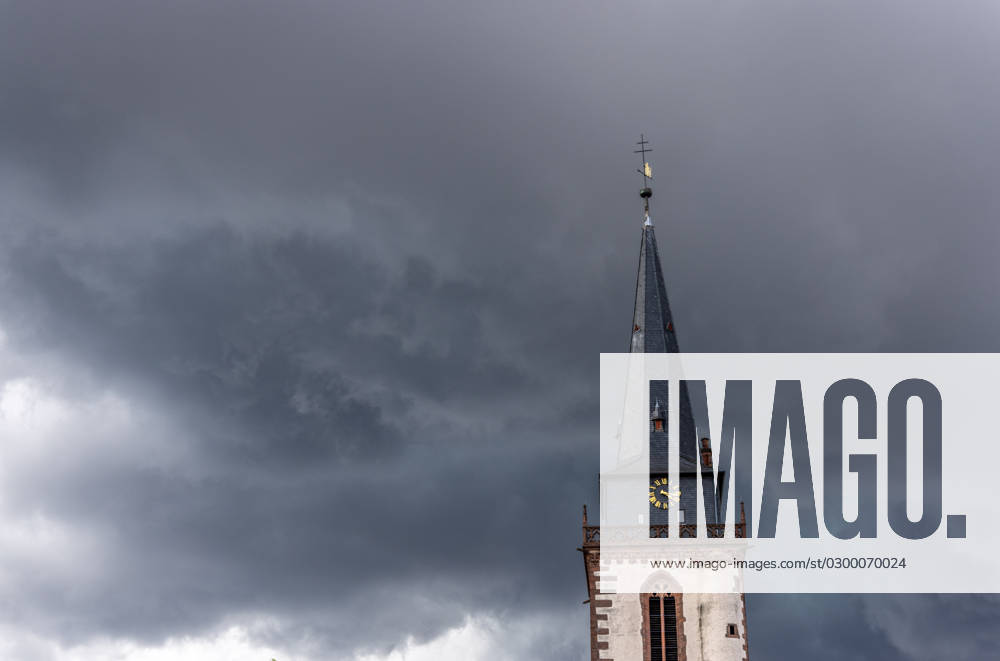 Dunkle Wolken über dem Kirchturm Dunkle Wolken eines Gewitters sind am Nachmittag am Himmel über dem Turm der katholischen Kirche St. Ursula zu sehen., Oberursel Hessen Deutschland