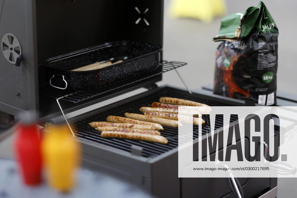 Grillwürste liegen auf einem Kohlegrill. Im Vordergrund Ketchup und Senf. (Themenbild, Symbolbild) Köln, 25.07.2023 NRW Deutschland