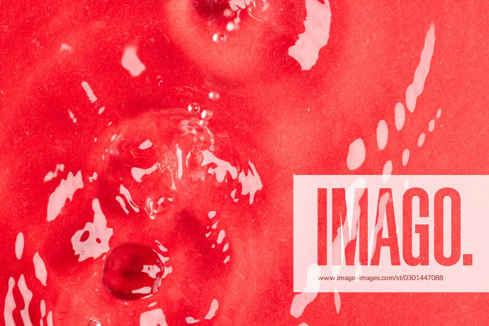 Close up of water drop falling into water with ripples and copy space on red background. Water, liquid and colour concept.