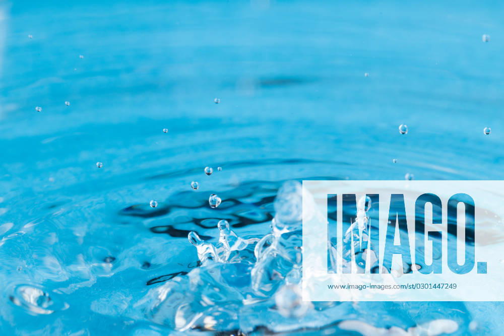 Close up of water drop falling into water with ripples and copy space on blue background. Water, liquid and colour concept.