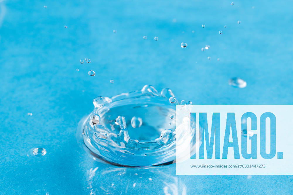 Close up of water drop falling into water with ripples and copy space on blue background. Water, liquid and colour concept.