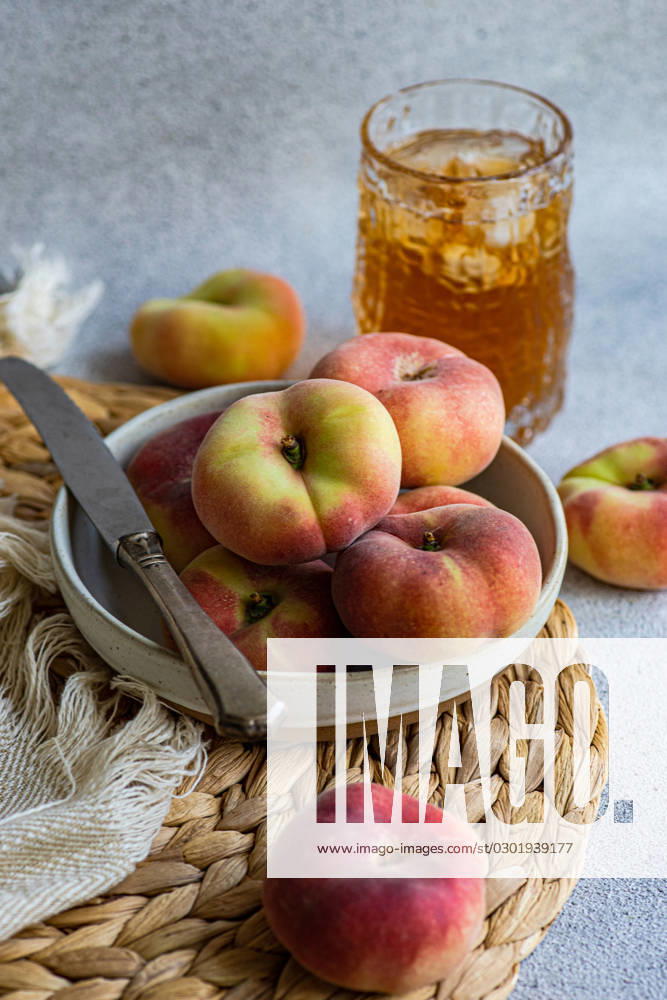 High angle of plate of zodiac peach variety and summer lemonade with ice and knife placed on napkin against blurred background Model Released AnnaBogush_ID16100_490197_002