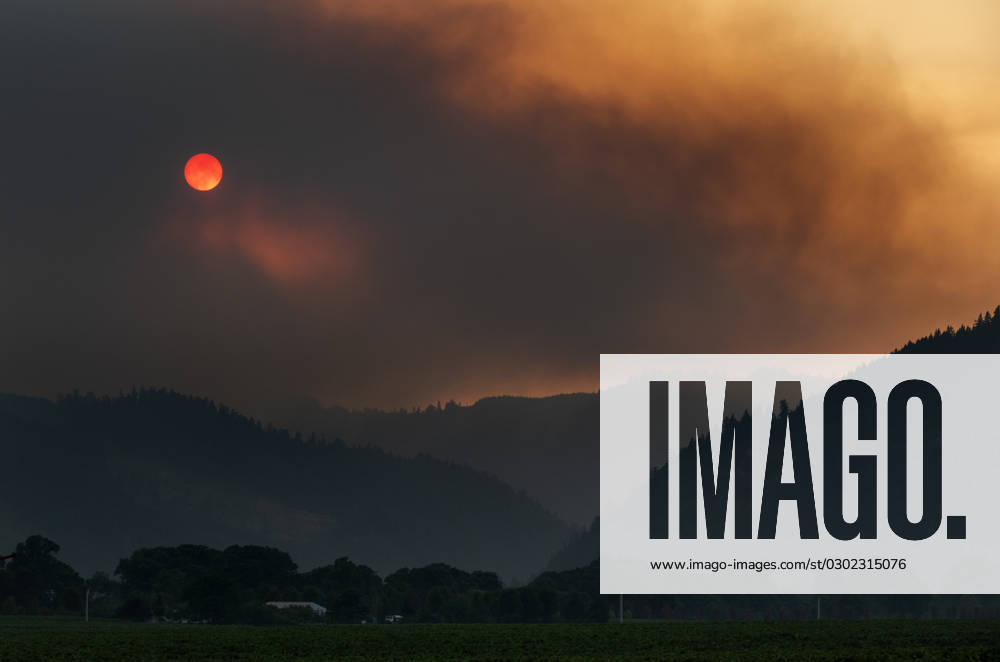 Heavy smoke from the southwest Oregon Cougar Creek Rattlesnake Ridge fire nearly blots out the setting sun in the mountains above vineyards and farms. The lightning caused fire has burned 1000 acres. Level three ‘Go Nowâ€⠢ evacuations have been ordered for residents in rural areas in the zone of potential fire growth. Umpqua USA - ZUMAl31_ 20230826_zaf_l31_001