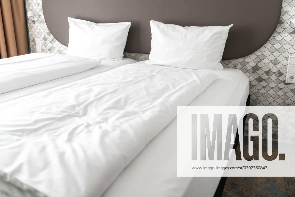 Bett in einem Hotelzimmer mit weißer Bettdecke und weißen Kissen