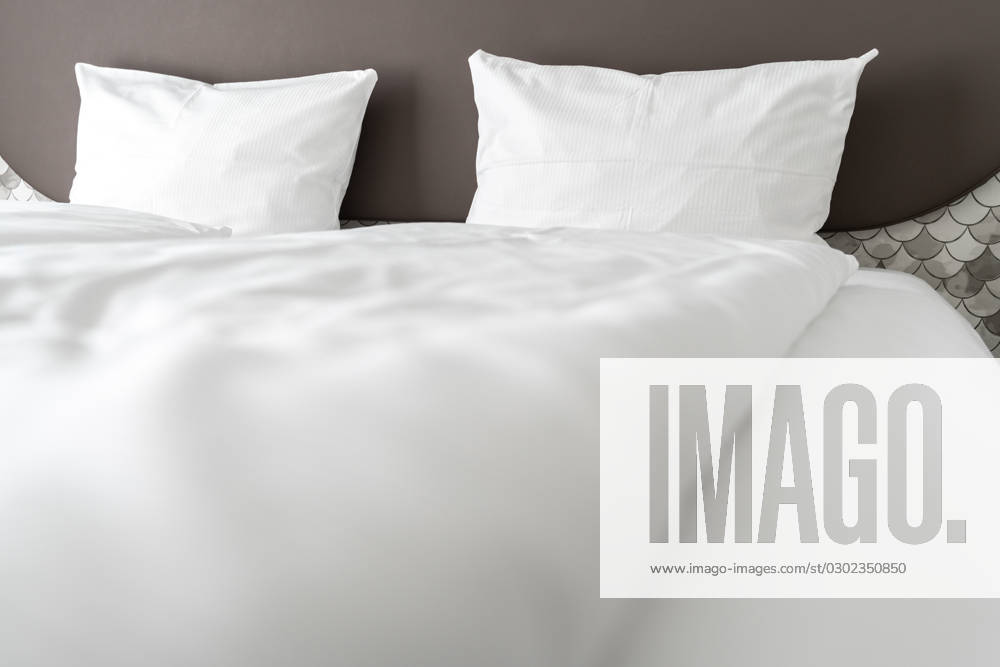 Bett in einem Hotelzimmer mit weißer Bettdecke und weißen Kissen