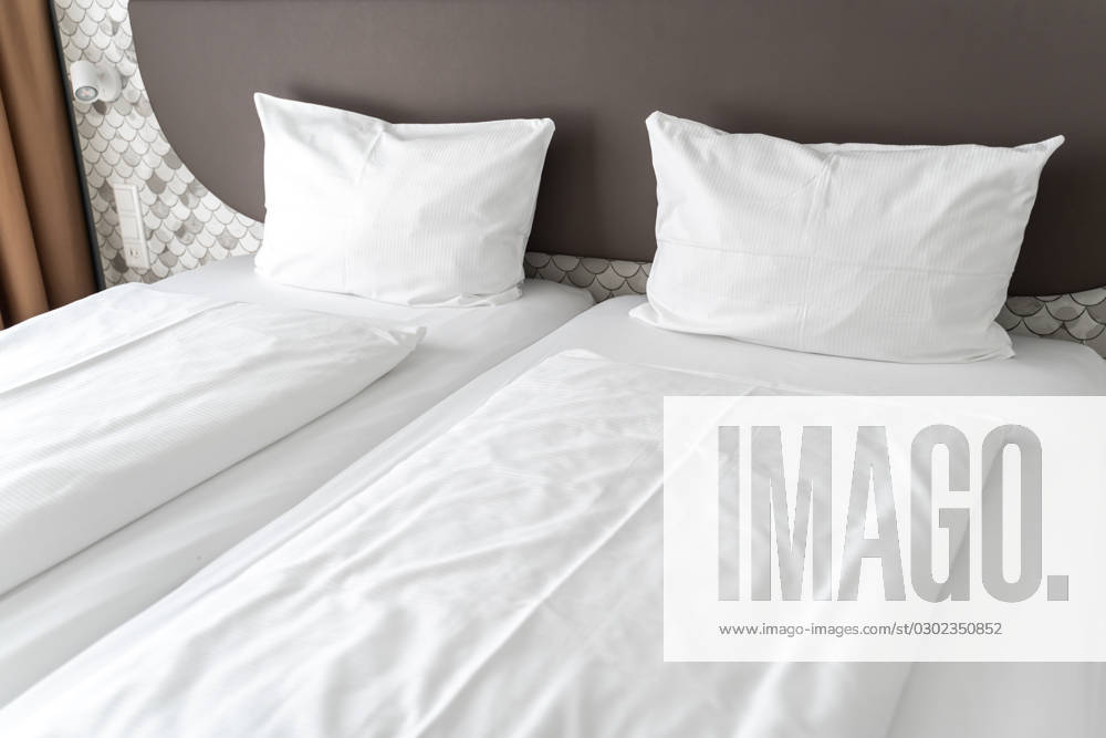 Bett in einem Hotelzimmer mit weißer Bettdecke und weißen Kissen