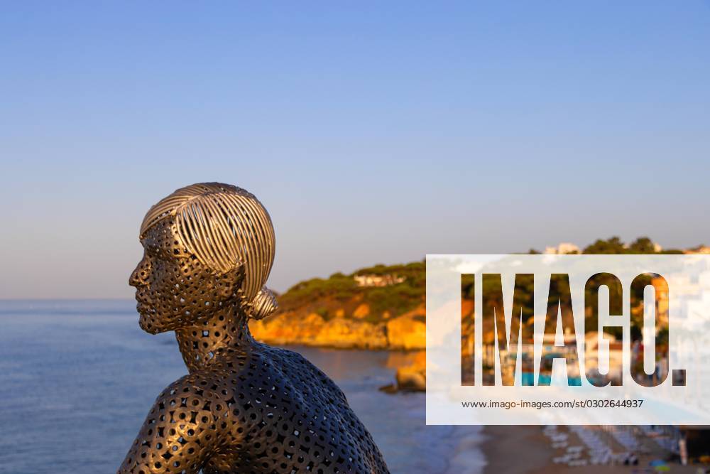 Eine Metall-Skulptur des Künstlers Carlos de Oliveira Correia blickt auf der Aussichtsplattform am Strand von Olhos des Augua kurz nach Sonnenaufgang auf den Atlantik hinaus., Algarve, Olhos des Agua, Faro, Portugal, Europa