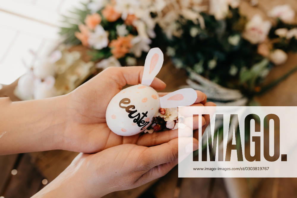 Young woman holding an easter egg with rabbit ears painted by children with flowers Model Released ElenaGonzalez_ID3561_115798_015