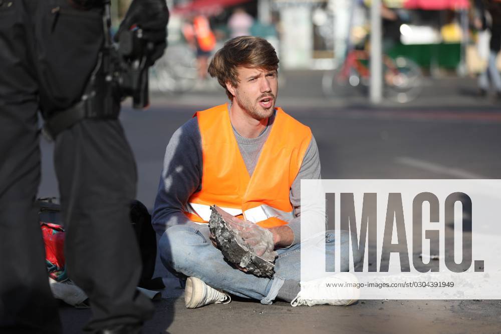 Berlin, Deutschland, 18.09.2023: Protest von Klimaaktivisten der Letzten Generation am Kottbusser Tor in Berlin-Kreuzberg. Polizisten lösen einen anbetonierten Aktivisten von der Straße.