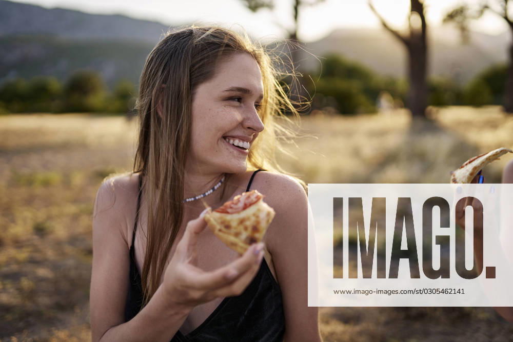 Happy woman having slice of pizza in park on weekend model released, Symbolfoto, ANNF00369
