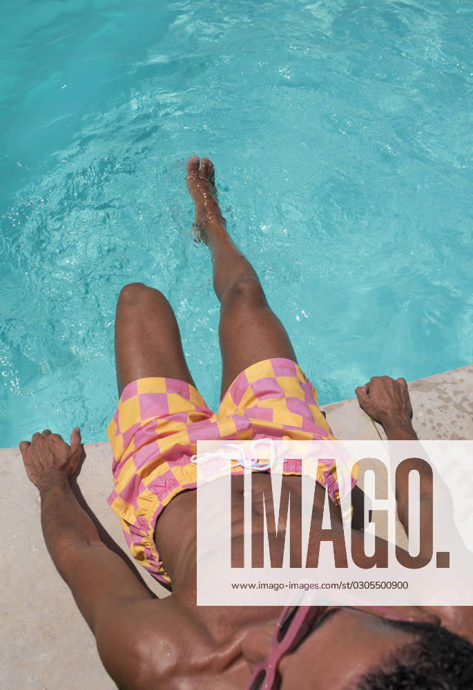 Young man sitting by poolside on sunny day model released, Symbolfoto, VRAF00149