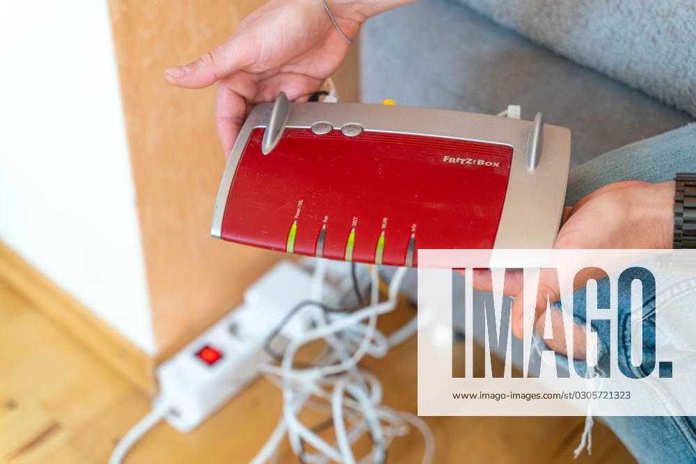 Ein Fritzbox Wlan Router in einer Wohnung. Mann hält den Fritz Box Router in der Hand
