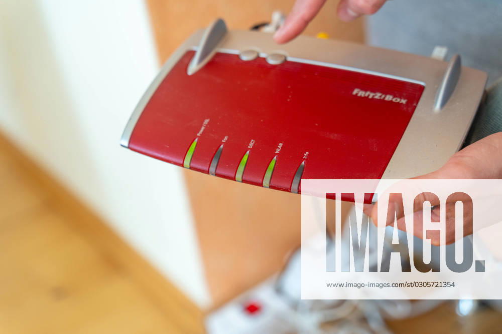 Ein Fritzbox Wlan Router in einer Wohnung. Mann hält den Fritz Box Router in der Hand