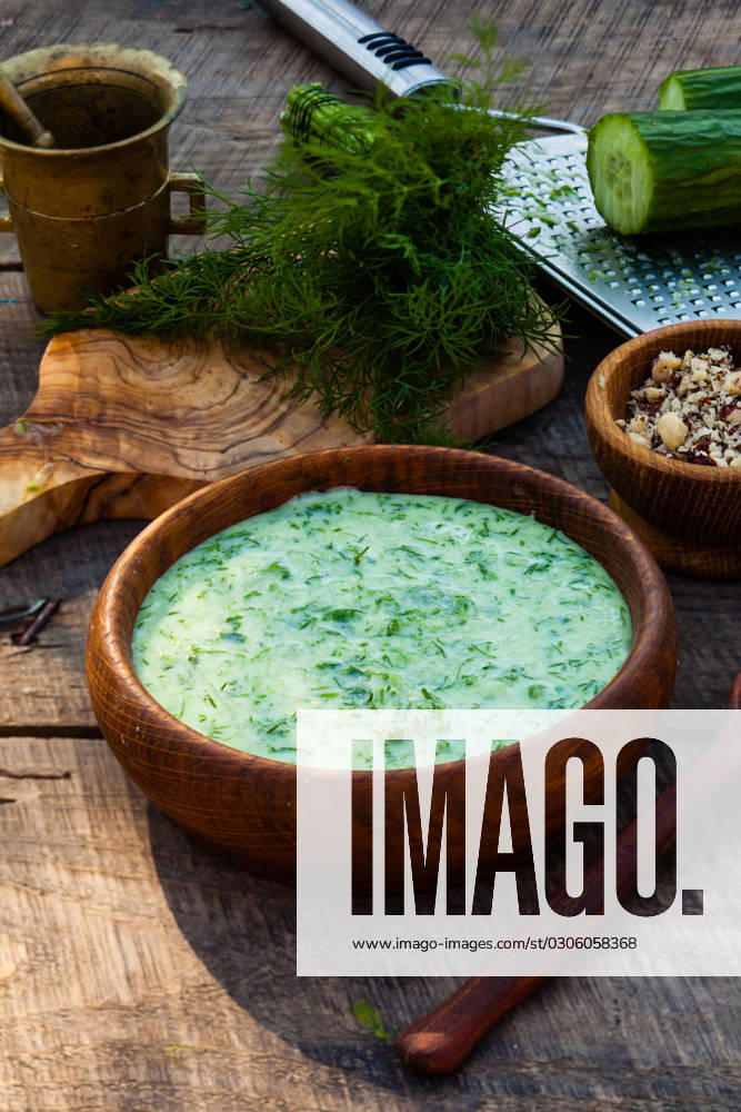 Homemade tarator with ingredients on wooden rustic background Homemade chilled tarator with ingredients on wooden rustic background. Traditional bulgarian summer cold soup with cucumbers, dill, garlic, yogurt and walnuts. ,model released, Symbolfoto