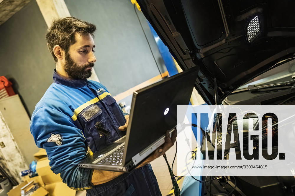 Mechanic perform chip tuning on tuned car in a garage workshop Milan, Italy 13 November 2022: Mechanic perform chip tuning on tuned car in a garage workshop Mechanic perform chip tuning on tuned car in a garage workshop