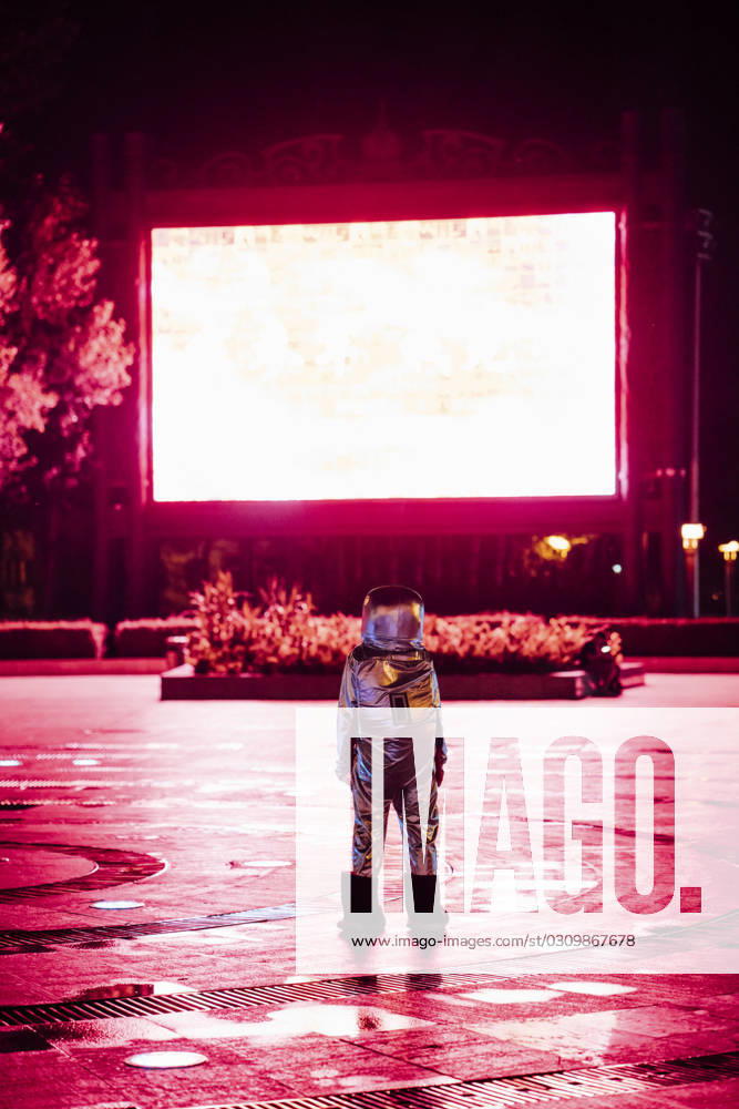 Spaceman on a square at night attracted by shining projection screen model released, Symbolfoto, VPIF00755