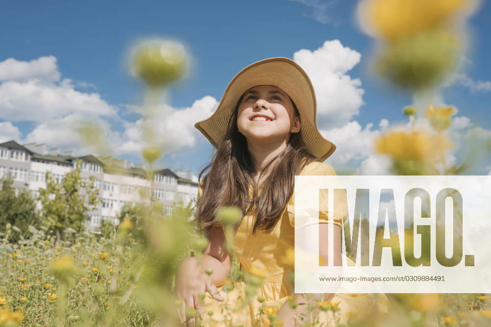 Contemplative girl wearing hat in flower field on sunny day model released, Symbolfoto, OSF01975