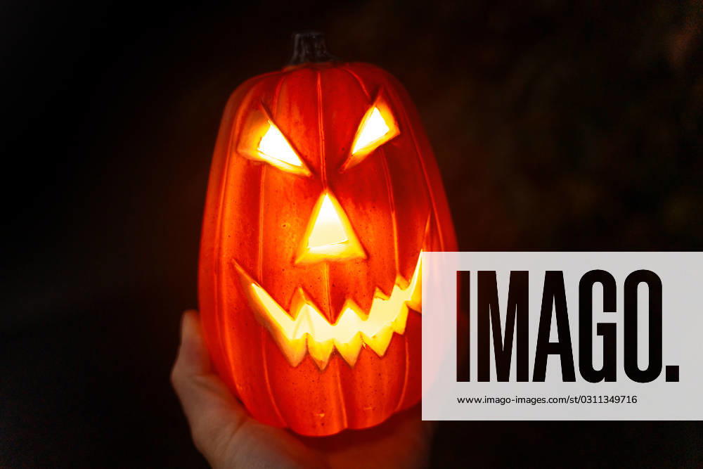 Hand holding scary Halloween pumpkin at night