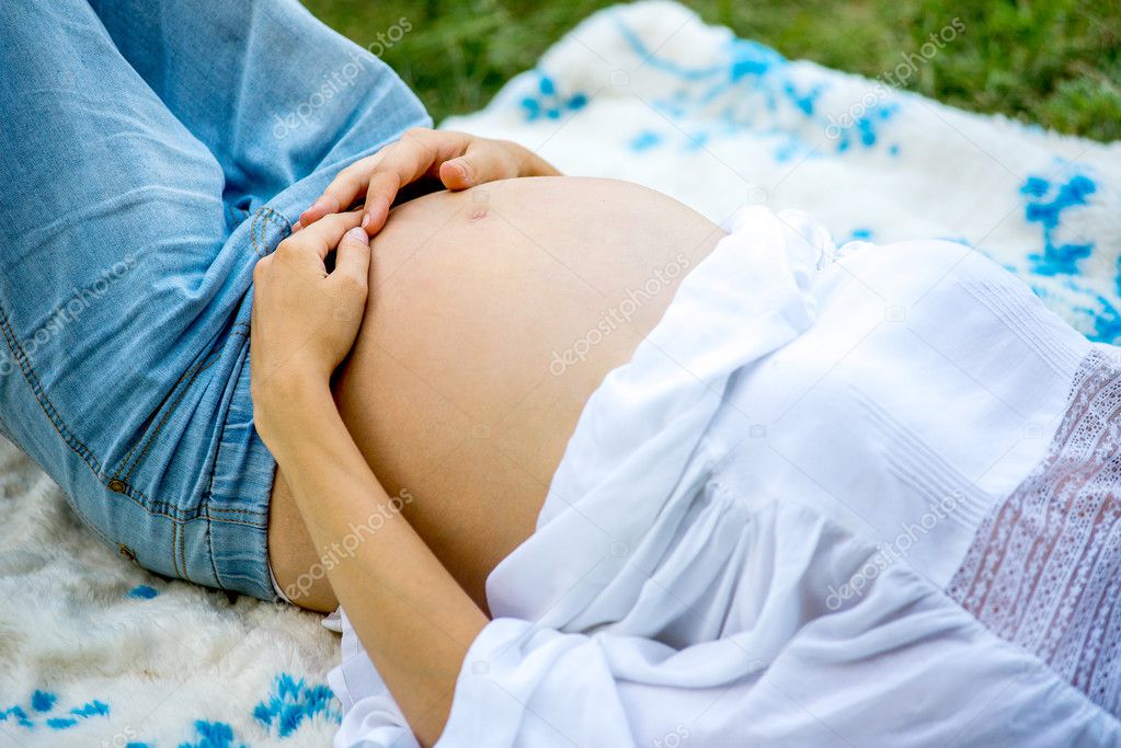 Pregnant woman walking in the park in the summer park. A girl prepares to become a mother. Walk in the fresh air.