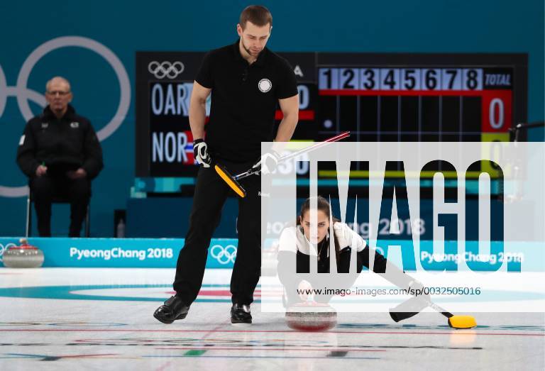 GANGNEUNG, SOUTH KOREA â€“ FEBRUARY 13, 2018: Curler Alexander Krushelnitsky (L) looks on as Anastasia Bryzgalova, Olympic Athletes from Russia, delivers a stone in their mixed doubles curling bronze medal match against Norway s Kristin Skaslien and Magnus Nedregotten during the 2018 Winter Olympic Games Olympische Spiele Olympia OS at the Gangneung Curling Centre. Olympic Athletes from Russia won the game 8:4. Valery Sharifulin TASS TS0738B1