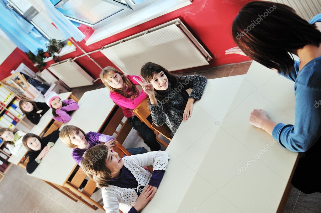 Happy young teacher woman at elementrary school teaching and giving leassons to group of young smart children model released