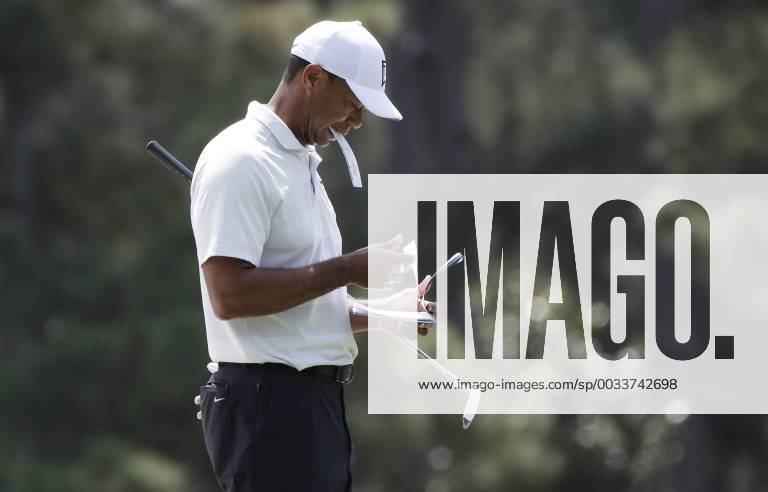 Tiger Woods holds a paper in his mouth on the first hole green in the 2nd round of the 2018 Masters Tournament at the Augusta National Golf Club in Augusta, Georgia, on April 6, 2018. AUG20180406129 JOHNxANGELILLO
