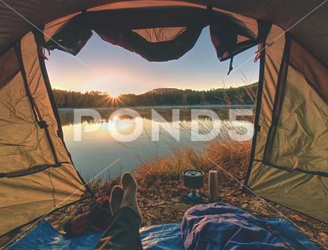 Couple legs rest in tent at lake. Hiker enjoy view outsid and e free hike vacation waterproof, water, vacation, trip, trekking, trees, tread, travel, tourist, tourism, together, toes, thermos bottle, tent, sunset, socks, sleeping mat, sleeping bag, scenery, rest, recreation, pure nature, outdoor, naked foot, nail, mountains, mountain, man body, landscape, lake, horizon, holiday, hiking, hiker legs, hike, grass, forest, foam mat, feet, dinner, couple, cooking breakfast, campsite, camping cooker, boyfriend, boots, beautiful, backpack, adventure, activity