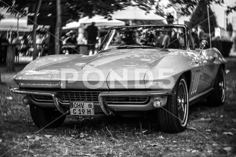 The sports car Chevrolet Corvette Sting Ray Convertible (C2). Focus on center. Swirly bokeh. Black and white. The exhibition of "US Car Classics". america, american, ancient, antique, auto, automobile, automotive, car, classic, design, diedersdorf, exhibition, germany, machine, model, nostalgia, old, oldtimer, retro, style, transport, transportation, us, usa, vehicle, vintage, exterior, 2-door, sports car, Chevrolet, Corvette, Sting Ray, Convertible, C2, second generation, GM, General Motors, muscle car, Focus, center, Swirly, bokeh, black, white