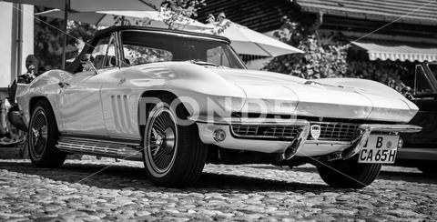 The sports car Chevrolet Corvette Sting Ray Convertible (C2), 1965. Black and white. The exhibition of "US Car Classics". exterior, vintage, 2-door, america, american, ancient, antique, auto, automobile, automotive, black, c2, car, chevrolet, classic, convertible, corvette, design, diedersdorf, exhibition, general motors, germany, gm, machine, model, muscle car, nostalgia, old, oldtimer, retro, second generation, sports car, sting ray, style, transport, transportation, us, usa, vehicle, white