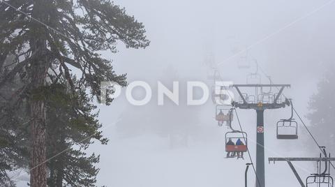 Ski lift in the fog, winter sports in bad weather. Mount Olympus ski resort, Cyprus chairlift, ski, lift, bad, weather, extreme, fog, blizzard, blurred, cable way, Chionistra, conditions, dense, dramatic, foggy, mist, mount, mountains, Olympos, Olympus, people, piste, resort, ropeway, silhouette, skier, skiing, snow, snowboarding, snowstorm, sports, trees, Troodos, visibility, white