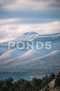 A beautiful landscape view of trees under snow cliffs against a gray sky in Matroosberg, South Africa abstract, background, beautiful, beauty, blue, cloud, clouds, geology, hill, landscape, Matroosberg, natural, nature, outdoor, outdoors, rock, scenic, sky, snow, South Africa, stone, sunny, texture, travel, tree, trees, vertical, view, water, white, winter